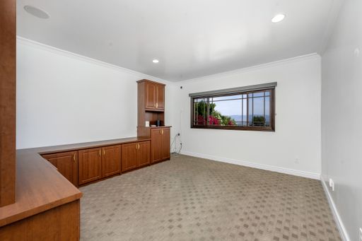 An empty room featuring a spacious wooden cabinet and shelves in Encino, California
