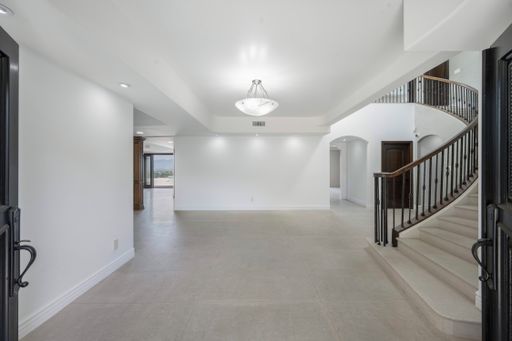 An elegant hallway with chandelier, staircase, and door