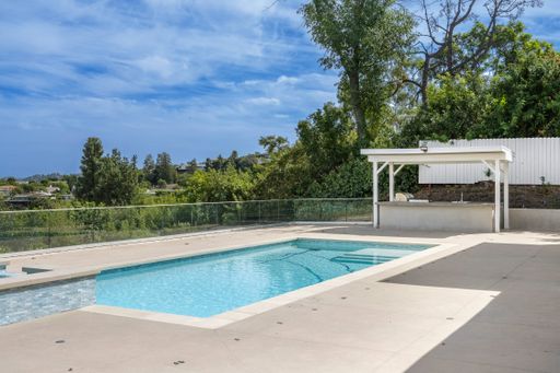 An exterior view of a house with a welcoming pool on the patio in Encino, California
