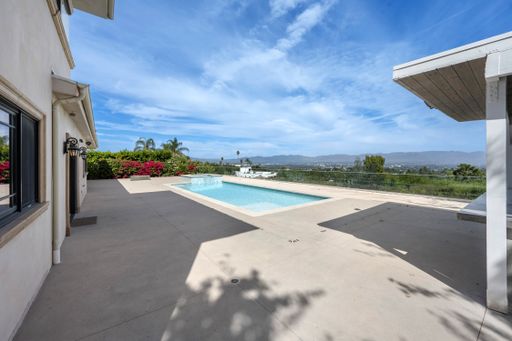 A pool with glass walls, viewed from a spacious patio in California
