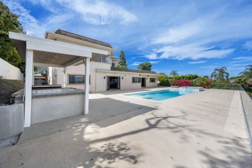 A large house with covered patio and pool in the front yard in California