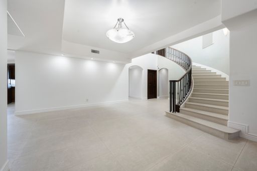 A contemporary foyer with marble floors, staircase, and abundant natural light in California