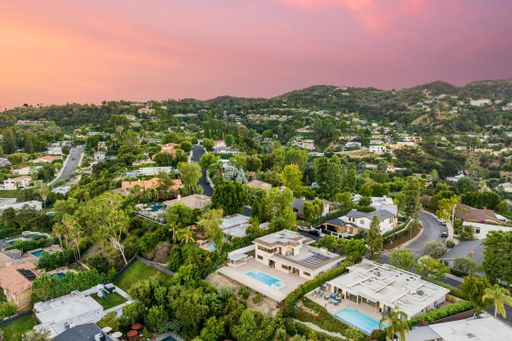 A sunset illuminating hills near house with a pool