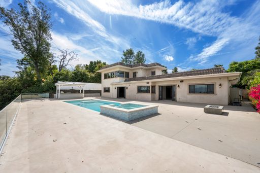 A swimming pool next to a house under cloudy sky in California