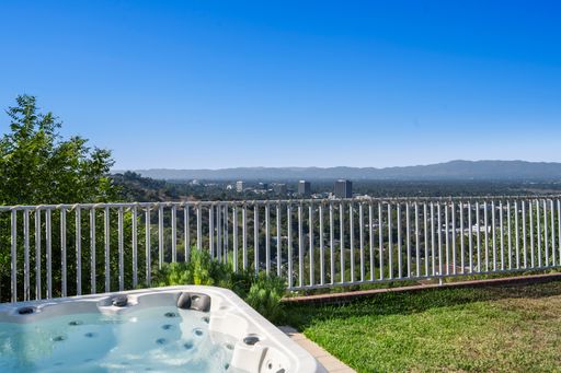 A hot tub sits on a lush green lawn near a wooden deck in Hidden Hills, CA