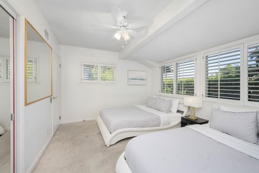 A minimalistic white bedroom with two beds and windows in Hidden Hills, CA