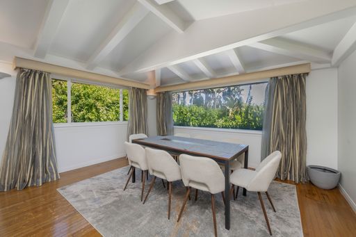 A table surrounded by numerous white chairs, with a window beside it in Hidden Hills, CA