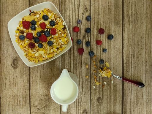 A top view of a bowl of fresh and delicious Granola and milk on a wooden table