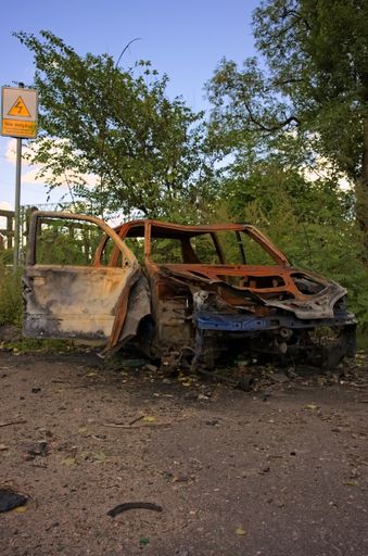 A vertical shot of an old rusty car at a scrapyard