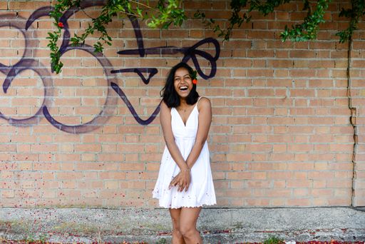 An East Asian female in an urban environment in front of a graffiti wall