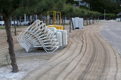 A closeup of folded sun loungers on the sandy beach in the morning