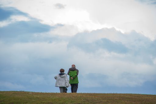 An old couple walking in the field in a cloudy weather