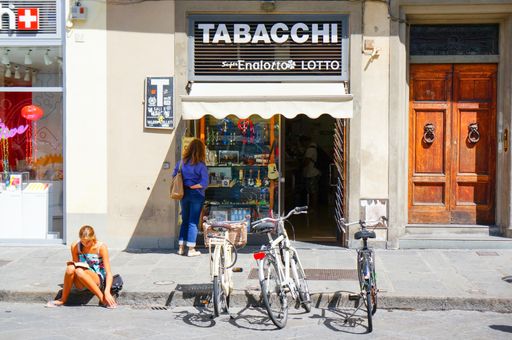 Bicycles and people in front of a small Tabacchi shop in the city center.