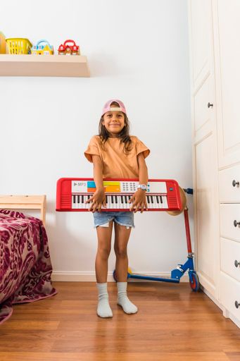 A young Hispanic girl holding piano at home