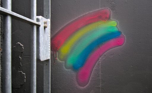 A graffiti of rainbow on a dark gray  wall and a metal door