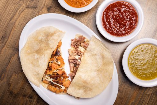 A closeu shot of Tacos Al pastor with different Mexican sauces