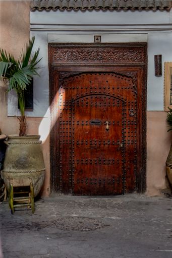 A beautiful and charming corner of Marrakech with a beautiful wooden door with the typical umbrella-head nails and bronze knocker to knock on the door