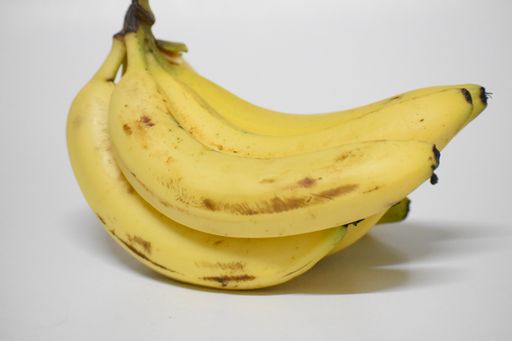 A closeup of a bunch of ripe bananas against a white background