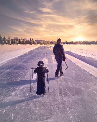 A vertical shot of an evening skate on a lake of father and son in Calgary AB, Canada
