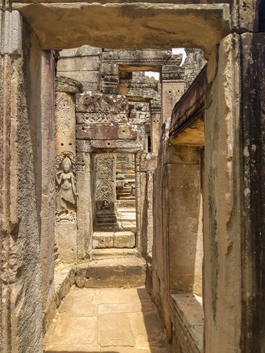 The narrow halls of Angkor Wat temple with religious carvings on its columns