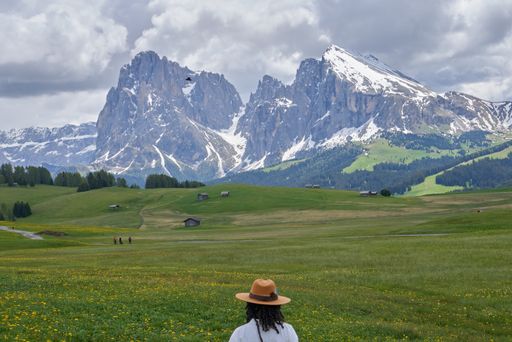 The beautiful landscape of a pasture with yellow flowers and in the background the mountain of Alpe di Siusi with a girl in the foreground in the It