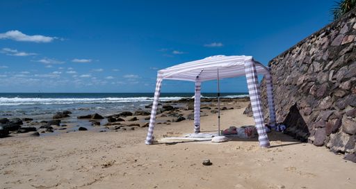 A small tent pitched close to a rocky beach wall