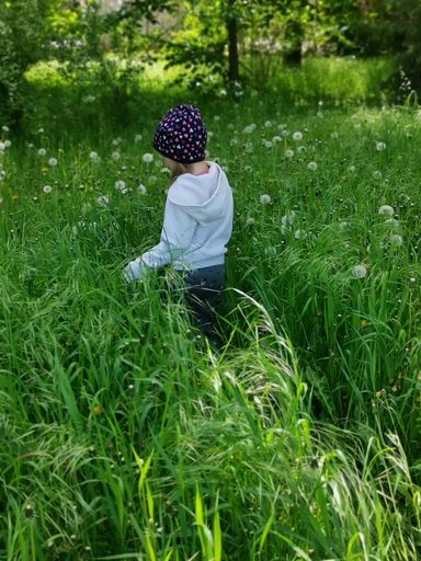 A vertical shot of a girl walking in a green meadow