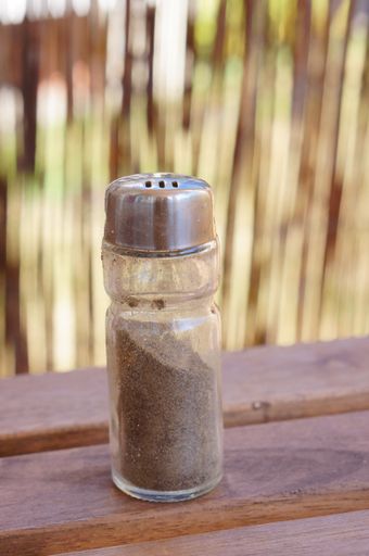 A vertical shot of ground black pepper on a wooden surface on a blurred background