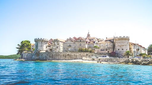 A wide shot of buildings of the Korcula Croatia on the shore near the sea on a sunny day