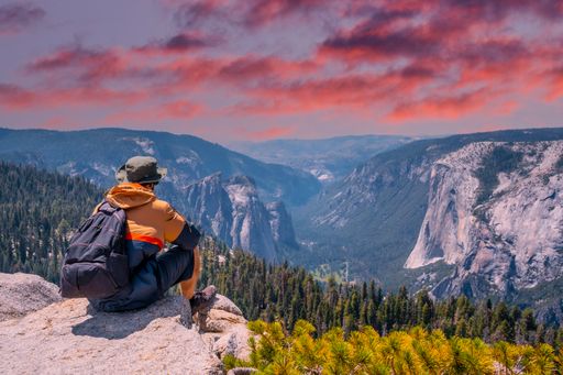 A person sitting at the cliff edge and of Taft point looking at Yosemite National Park and El Capitan