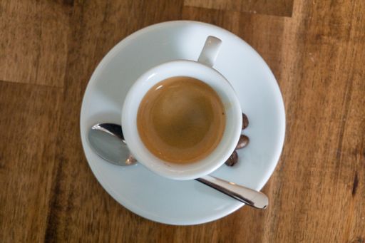 A high angle shot of a cup of coffee with a spoon on a wooden table