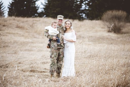 A young family portrait - a soldier father holding his son and a beautiful young wife wearing a white dress
