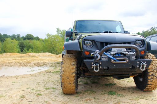 A muddy off roader with big muddy tires equipped with bullbars rhino bars tow shackles and winch