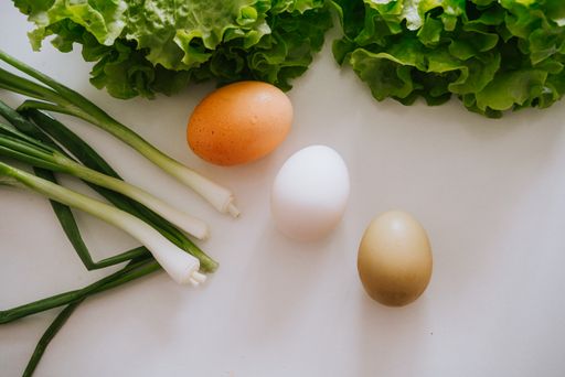 A closeup of eggs, spring onions and lettuce on a dining table