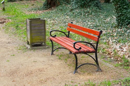 A wide angle shot of a bench next to a trash can in the park