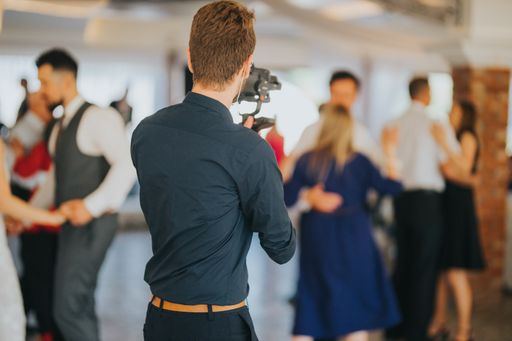A shallow focus of a young photographer filming a wedding in a restaurant