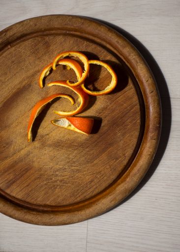 A top view of fresh orange peels on a wooden plate
