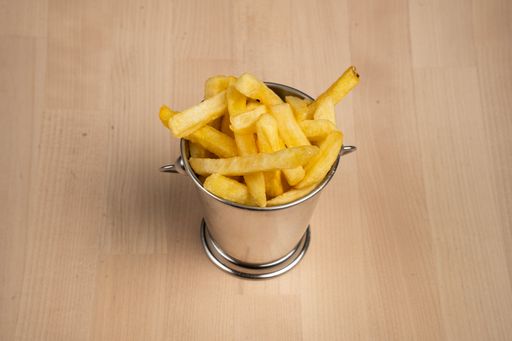 A top view of crispy fries in a metal pail, set on a rustic wooden surface
