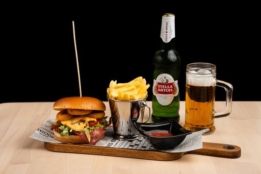 A tray with a bottle and a glass of Stella Artois beer, cheeseburger, and fries.