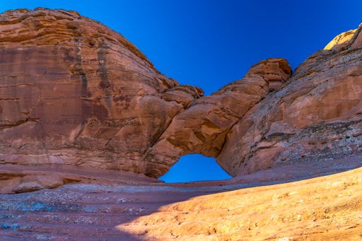 A tall rock formation with an arch carved into it against the sky at Arches National Park, Utah