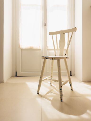 A boho style bathroom bathed in soft day light with a wooden vintage stool