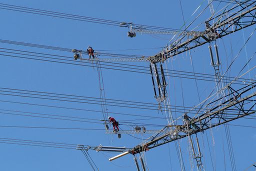 A team of workers on a high voltage pole repairing wires. Germany