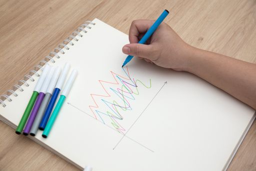 A high angle shot of female hands drawing with colorful pens in a notepad