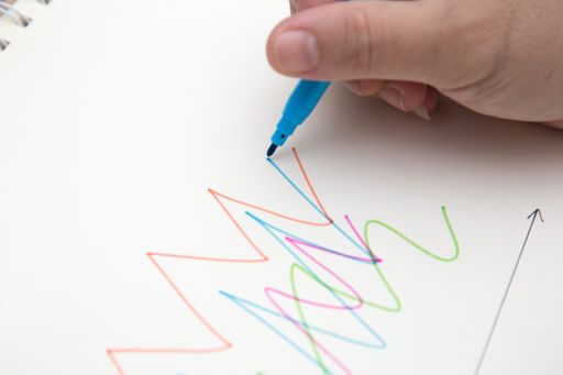 A closeup shot of a female hand drawing with a blue pen on white paper