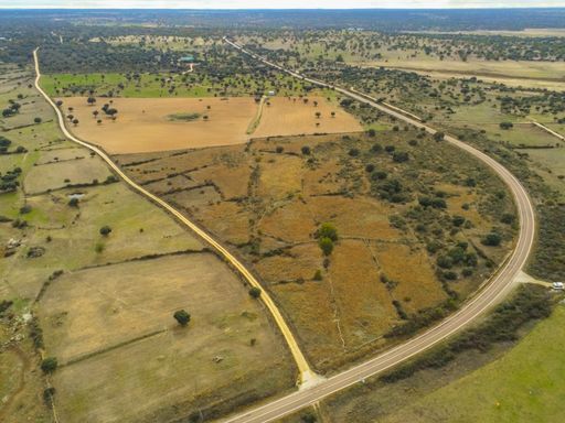 An aerial shot of a road in the middle of grassy fields in Salamanca, Spain
