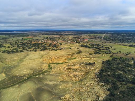 An aerial shot of grassy fields under a cloudy sky in Salamanca, Spain