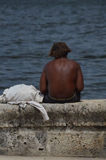 A vertical shot of a man from the back fishing on the Havana seawall
