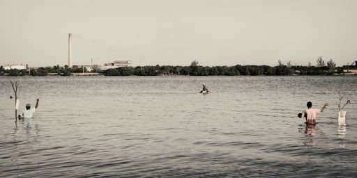 A view of fishers standing in water with half of their bodies covered by the seawater