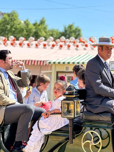 Women in traditional flamenco dresses on a horse-drawn carriage at the Feria de Abril also known as The Seville Fair