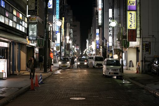 Busy urban street with cars and people at night in the city district